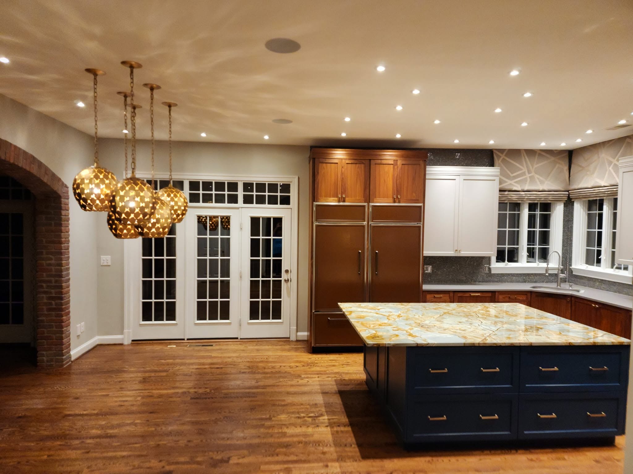 Completed kitchen cleaning with a stone island, wood cabinetry, and hardwood floors